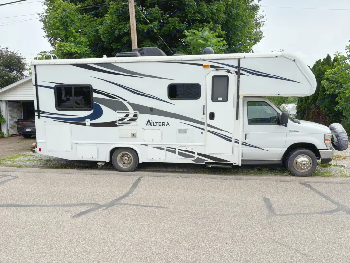 This white Altera Class C RV rental, with black/gray decals and roof AC, is parked roadside. Ready for your motorhome adventure!. Holiday Rambler Altera 2018