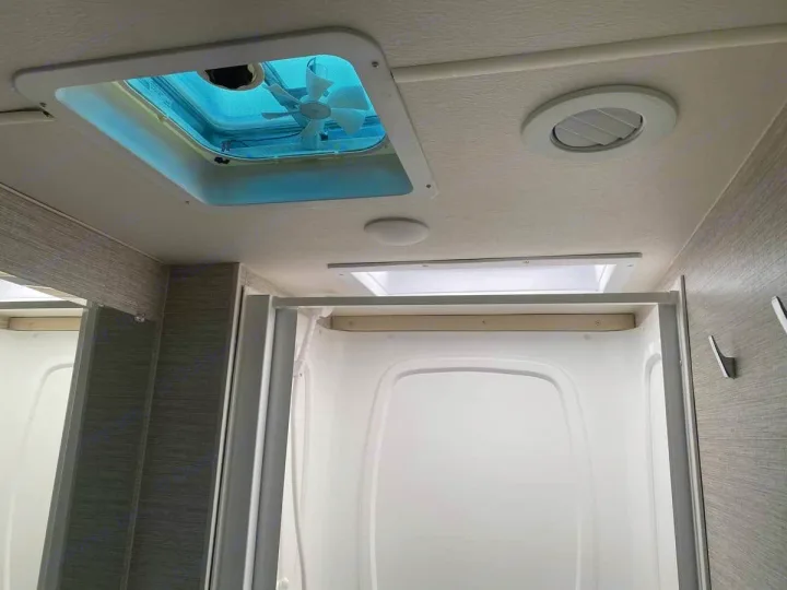 RV rental interior: A bright bathroom ceiling with a skylight fan and air vent above a pristine shower stall.. Winnebago Spirit R24742 2025