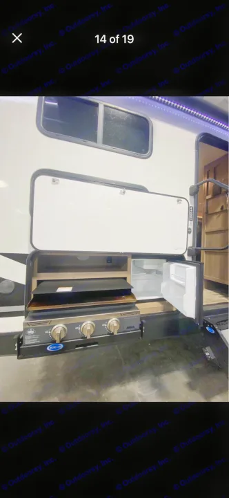RV rental's exterior kitchen, featuring a pull-out griddle, mini-fridge, and storage. Ideal for convenient outdoor cooking.. Grand Design Imagine 2022