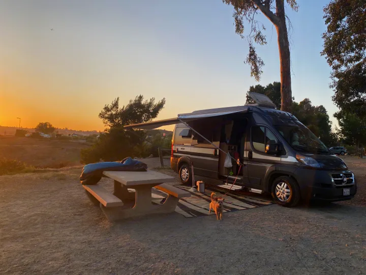 Golden hour camping in an **RV rental**! A camper van, picnic table, and dog are set up at a scenic, pet-friendly spot.. Hymer Hymer Class B 2019