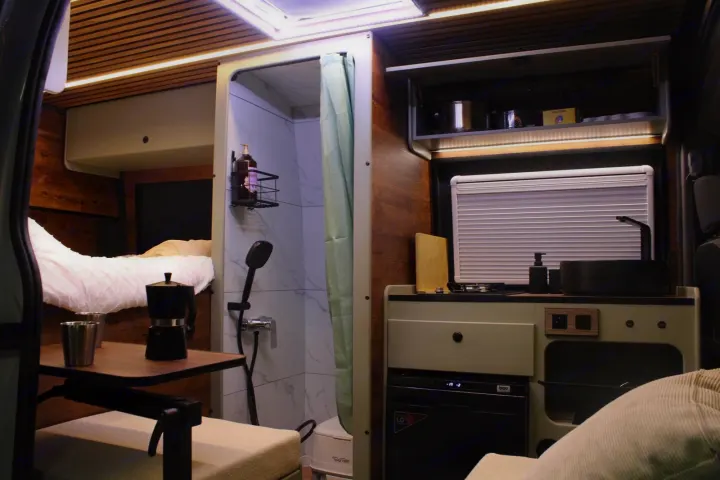 Compact RV interior: shower, kitchen, and bed are neatly arranged. This functional rv rental offers modern comforts.. renault Master 2,5TDI 2019