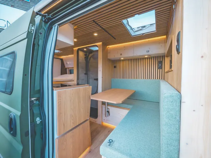 Step inside this inviting rv rental campervan. Features include a cozy dining area, shower, and bed in a modern, wood-paneled interior.. Peugeot Boxer 2019