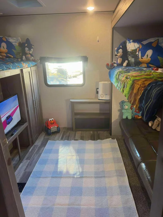 Cozy RV rental kids' bunk room featuring Sonic decor, toys, TV, and a comfy rug for play.. Crossroads RV Zinger 2024