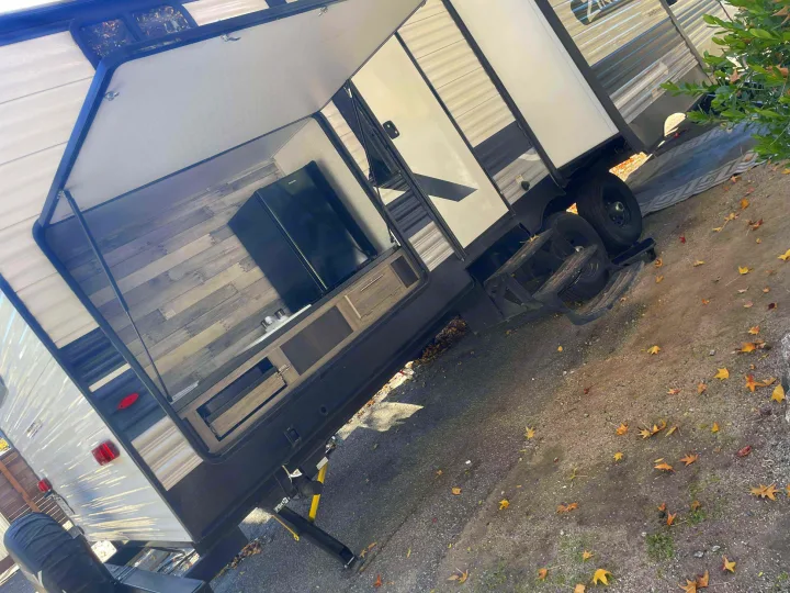 Experience an RV rental with this modern travel trailer, showcasing a convenient outdoor kitchen featuring a fridge, sink, and cabinets.. Crossroads RV Zinger 2024