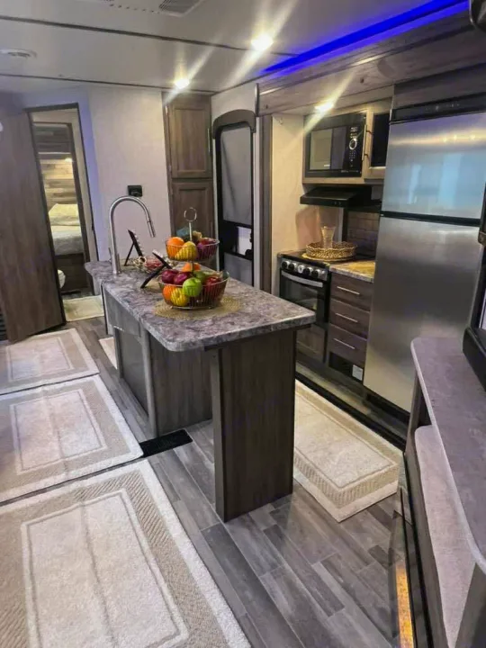Spacious rv rental kitchen with a large stainless steel fridge, microwave, stove, and an island sink.. Crossroads RV Zinger 2024