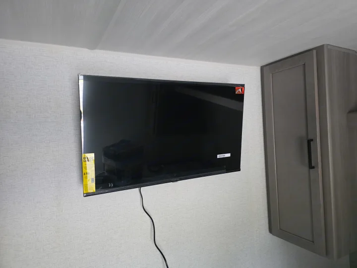 RV rental amenities: A black Insignia TV is mounted on a textured wall next to a gray cabinet with a black handle.. Keystone RV Hideout 2025