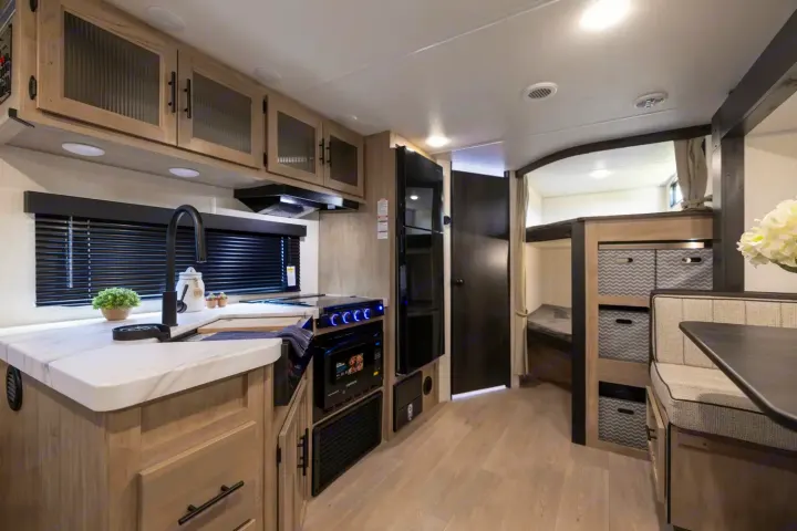 Explore this modern RV rental's compact interior, featuring a full kitchen, dining booth, and cozy bunk beds.. Forest River Cherokee Grey Wolf 2025