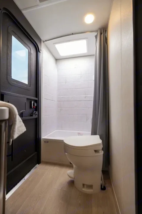 This RV rental offers a compact, bright bathroom with a shower/tub, toilet, and wood-look flooring for comfort.. Forest River Cherokee Grey Wolf 2025