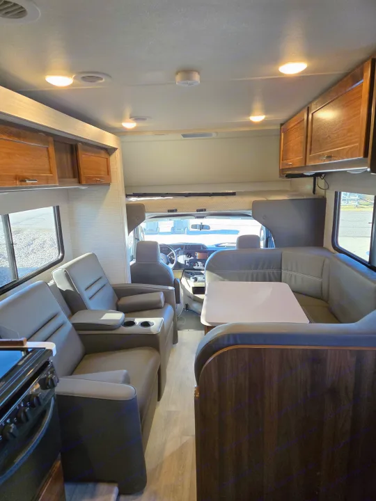 Bright and spacious rv rental interior with gray recliners, a dinette, kitchen corner, and front cockpit.. Winnebago Minnie Winnie 2020