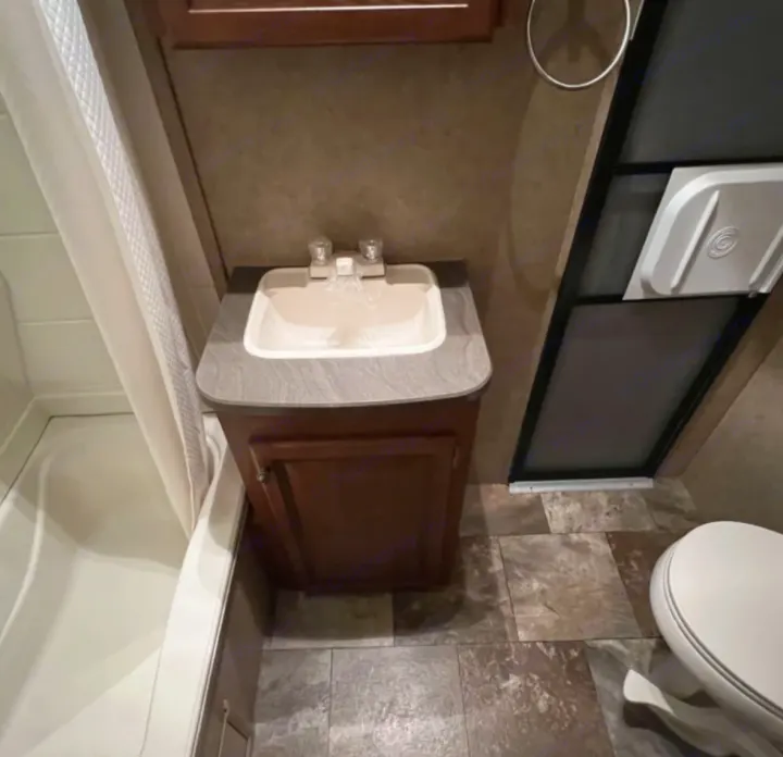 This RV rental features a neat, compact bathroom with a sink vanity, shower stall, and toilet, designed for travel convenience.. Jayco Eagle 2014