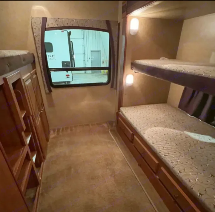 Spacious RV rental bunk room featuring twin bunk beds, under-bed storage drawers, built-in shelves, and a window.. Jayco Eagle 2014