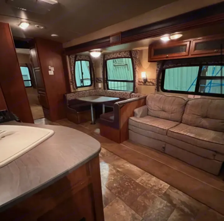 Cozy RV rental interior featuring a dinette, sofa, and kitchen counter, ready for your next adventure.. Jayco Eagle 2014