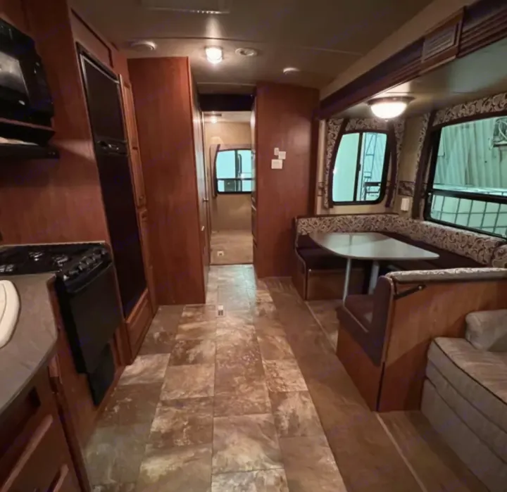 View inside an RV rental showing a kitchen with appliances, dinette with table, and a comfortable living area.. Jayco Eagle 2014