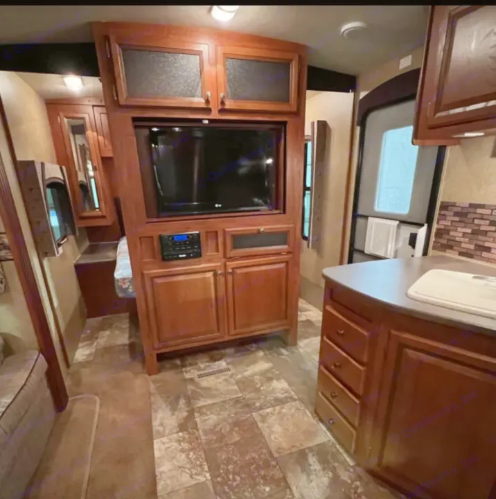 RV rental's inviting interior: Features a wood entertainment center with TV, kitchen counter, and access to a sleeping area.. Jayco Eagle 2014