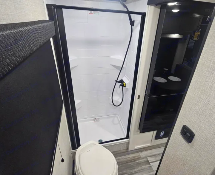 Modern RV rental bathroom: A compact space with a white shower, toilet, and sleek dark cabinetry, ready for your travels.. Jayco Jay Feather Air 2025