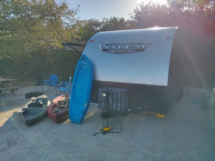 RV rental at a sunny campsite with a Salem Cruise Lite, blue, green, and red kayaks, and camping gear.. Forest River Salem Cruise Lite 2021