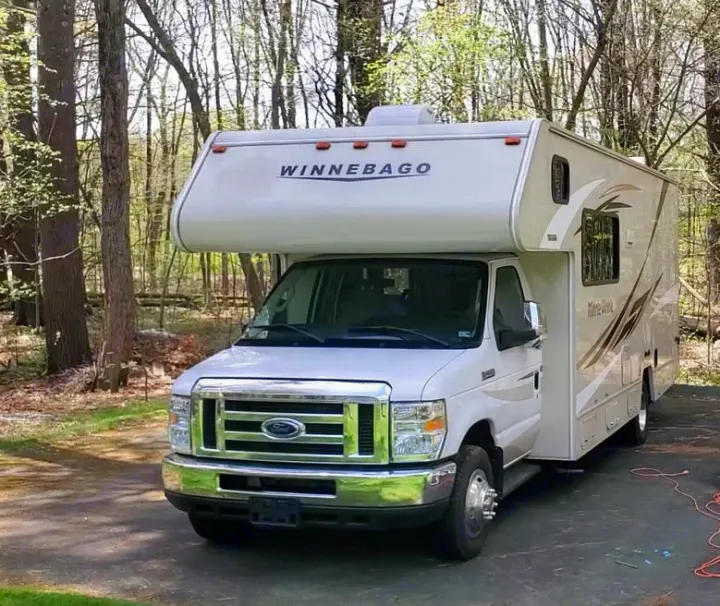 White Winnebago Class C motorhome rv rental parked in a wooded driveway. Ready for camping trips & travel adventures.. Winnebago Minnie Winnie 2018