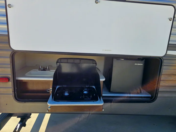 Enjoy your RV rental with this convenient outdoor kitchen: a sink, a two-burner Suburban stove, and an RVISION mini-fridge.. Avenger ATI 2019