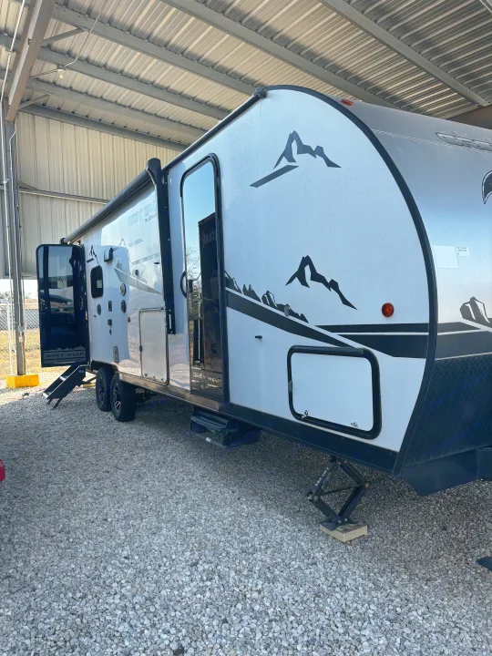 Grey Wolf Black Label travel trailer, ideal for rv rental, parked on gravel under a shelter, with doors open and steps down.. Forest River Cherokee Grey Wolf 2022