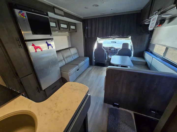 Bright RV rental interior with kitchen, sofa, dinette, and front cabin ready for adventure. Dog magnets on fridge.. Forest River Coachmen Leprechaun Premier 2022