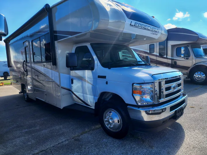 A clean white and gray Coachmen Leprechaun Class C motorhome is ready for an rv rental adventure, parked on asphalt under a blue sky.. Forest River Coachmen Leprechaun Premier 2022