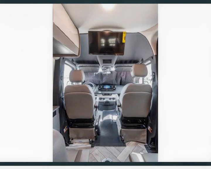 RV rental's inviting cabin: front seats, overhead storage, and a TV make this camper van comfortable for travel.. Thor Tranquility 2025