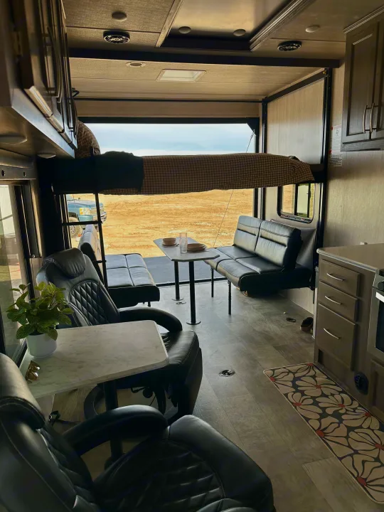 Spacious RV rental interior with dinette, bunk bed, recliners, and open back ramp, ideal for versatile travel.. Genesis Supreme Powerlite LE Toy Hauler 2022