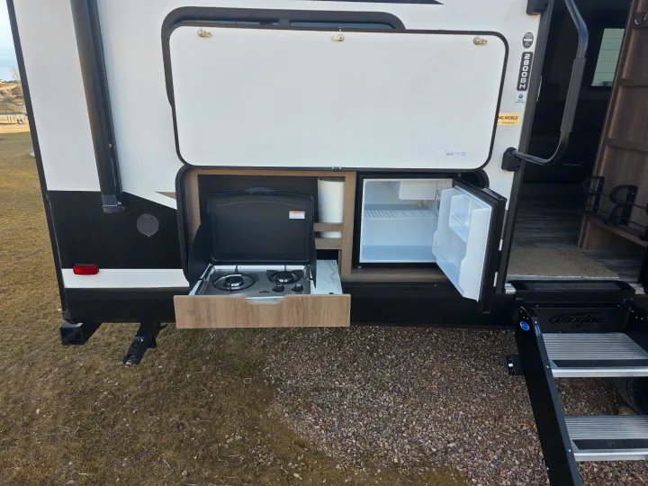 This RV rental features an exterior kitchen: a pull-out stove, mini-fridge, and shelves, ideal for camping adventures.. Grand Design Imagine 2022