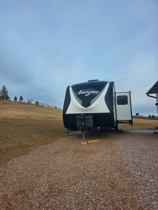 This Grand Design Imagine travel trailer RV rental is ready for adventure, parked on a gravel lot under a cloudy sky.. Grand Design Imagine 2022