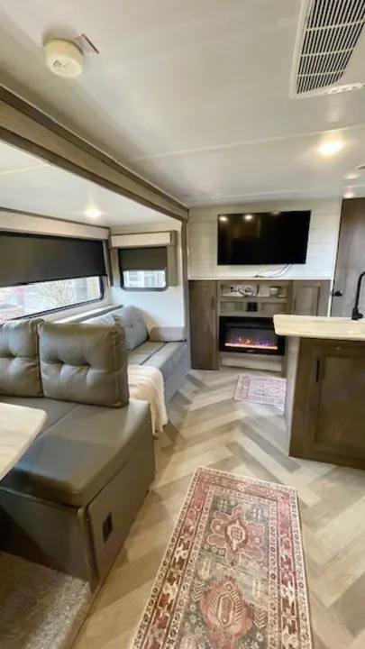 RV rental living space: comfy dinette, entertainment center with fireplace, TV, and modern herringbone flooring.. Forest River Salem Cruise Lite 2021