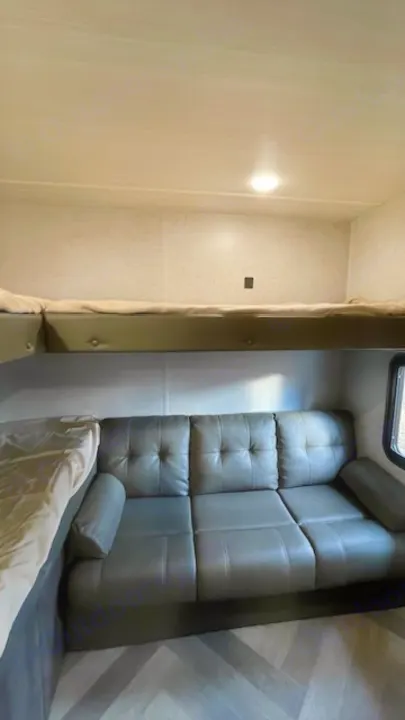 RV rental: Bunk beds above a grey sofa with herringbone floors inside a cozy, bright interior. Perfect for trips!. Forest River Salem Cruise Lite 2021