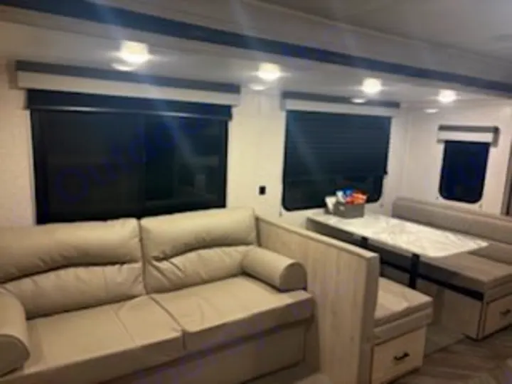 Enjoy this modern RV rental interior, featuring a cozy sofa and a practical dinette for dining or relaxing on your travels.. East to West Della Terra 2023