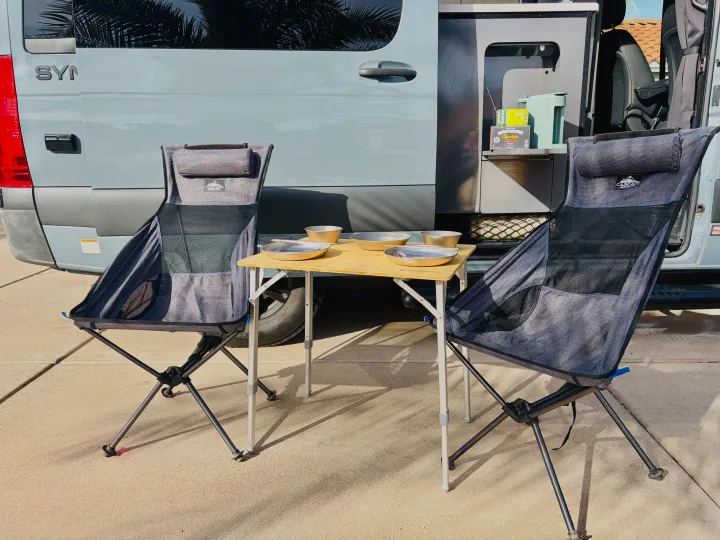 Perfect rv rental setup: portable camping chairs, table with bowls, and coffee/tea station next to the van.. Thor Synergy 2022