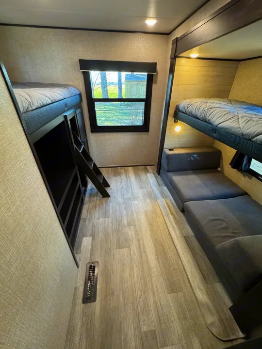 Spacious rv rental interior featuring comfortable bunk beds, a modular lounge area, and a large window for natural light.. Jayco Jay Flight SLX 2022