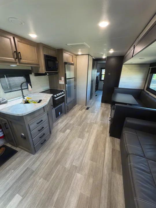 Bright rv rental interior showcases a modern kitchen, U-shaped dinette, and comfortable living space with light wood-look flooring.. Jayco Jay Flight SLX 2022
