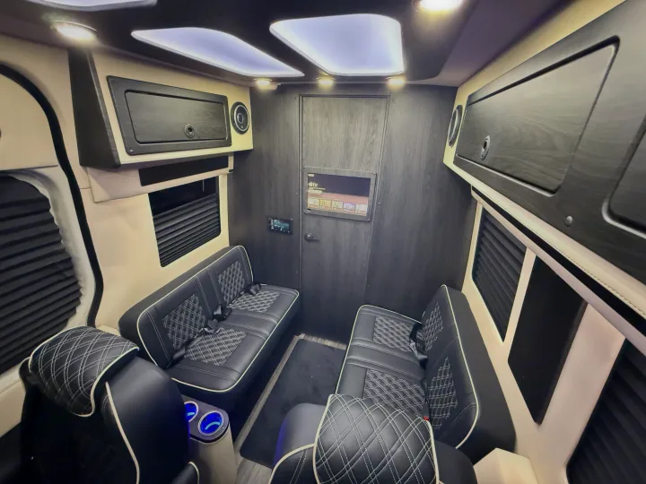 Luxury RV rental interior with custom black leather seating, wood paneling, entertainment system, and ambient lighting.. OGV Luxury Coach V-Cruise 2026