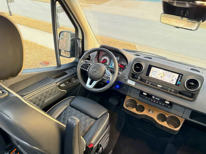 RV rental driver's view: Mercedes cockpit, luxurious leather seat, modern dashboard with 360 camera, wood accents.. OGV Luxury Coach V-Cruise 2026