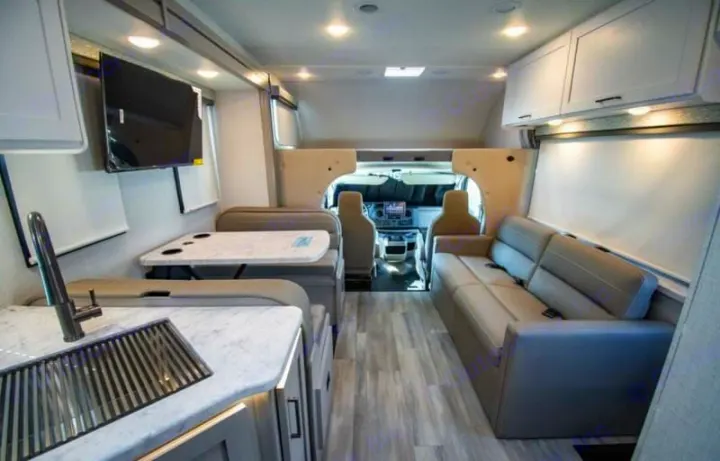 Modern rv rental interior with kitchen, dinette, sofa, TV, and cockpit access. Ideal for comfortable travel adventures.. Thor four winds 2027