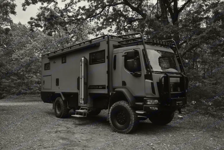 An imposing Storyteller GX EPIC expedition rv rental, seen in black and white, with an open side door and steps, parked on gravel in a forest.. Storyteller Epic 2025