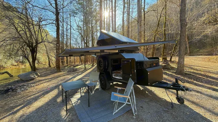 Riverside rv rental campsite with an off-road camper trailer, awning, table, & chairs. Perfect nature escape.. Cedar Ridge Deneb XT 2025