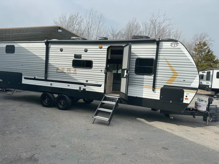 A PUMA Camping Edition travel trailer, gray with black accents, showing an open door with steps, ideal for an rv rental adventure.. Forest River Palomino Puma Camping Edition 2025