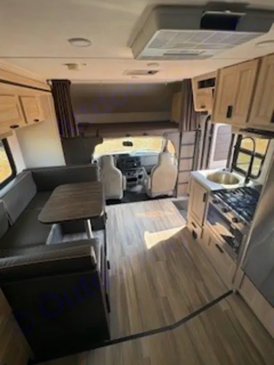 Step inside this RV rental! View of the kitchen on the right, U-shaped dinette to the left, and an overhead sleeping bunk.. Forest River Sunseeker LE 2024