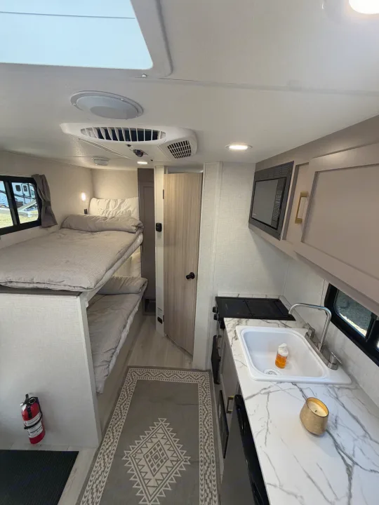 Experience comfort in this rv rental. Features bunk beds, a compact kitchen with a sink & microwave, and modern interior.. KZ Sportsmen Classic 130BH 2026