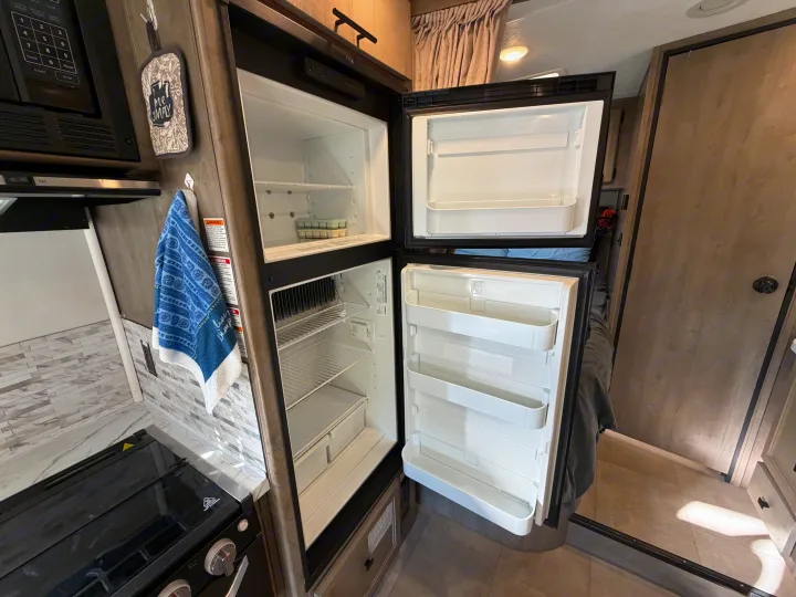 RV rental kitchen: Open fridge/freezer, microwave, and stovetop in a compact interior setup.. Coachmen Other 2020