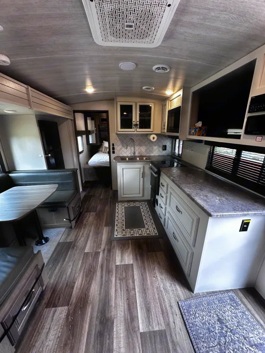 Spacious and modern RV rental interior featuring a full kitchen, dining area, and cozy bedroom. Perfect for travel.. Keystone RV Cougar 2023