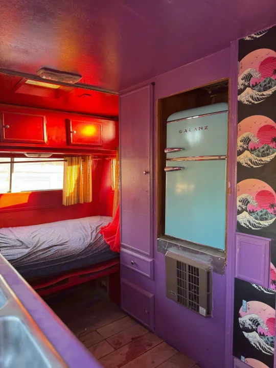 Vibrant retro RV rental interior featuring a light blue Galanz fridge, red accents, purple walls, and Hokusai-style art.. Kit Kit Trailer Deluxe 1978