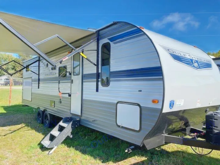 This grey Gulf Stream travel trailer with an extended awning and deployed steps is ready for your rv rental adventure.. Gulf Stream Ameri-Lite 2023