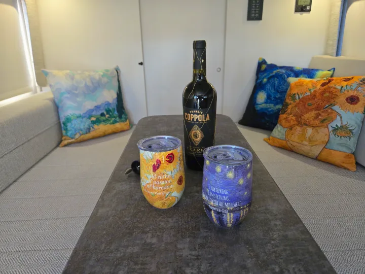 Enjoying wine in an RV rental! Francis Coppola Claret, Van Gogh art tumblers, and pillows create a cozy travel vibe.. Entegra Coach Ethos 2025