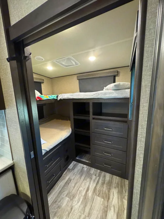 RV rental interior: bunk bed room with two beds, integrated drawers, and shelves for storage. A cozy space for travelers.. Grand Design Reflection 2022