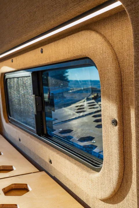 Inside an RV rental: a window offering nature views, sleek LED lighting, and a modular wooden bed platform. Ready for adventure.. Ram Promaster 2015